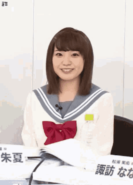 a woman in a sailor suit is sitting at a table with a bottle of water .