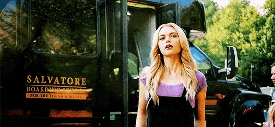 a woman is standing in front of a bus that says salvatore on the side .