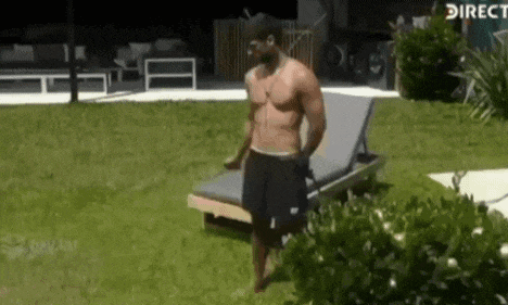 a shirtless man is standing next to a lawn chair in a yard .