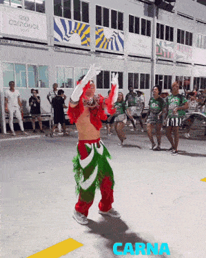 a man in a red and green outfit is dancing in front of a sign that says carna