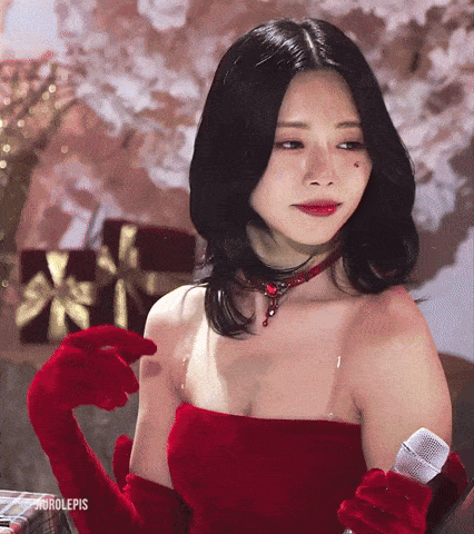 a woman wearing a red dress and red gloves is holding a microphone