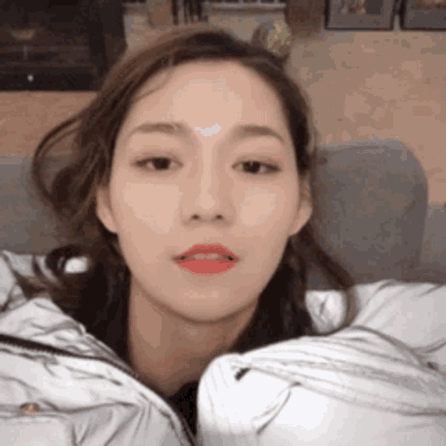 a woman with red lipstick is sitting on a couch and looking at the camera