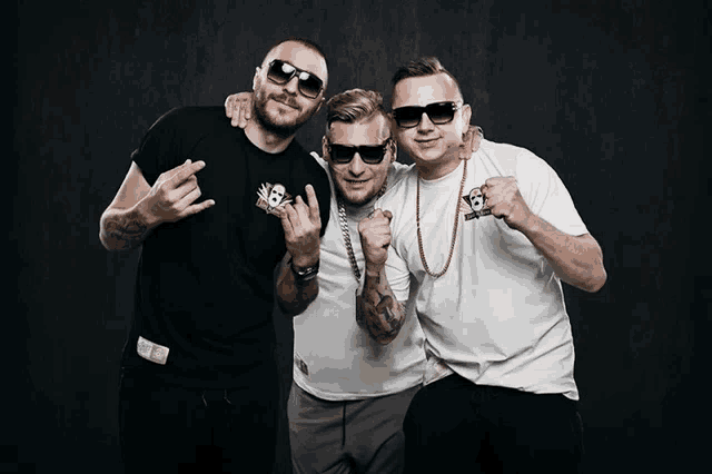 three men posing for a picture with one wearing a white shirt with the number 12