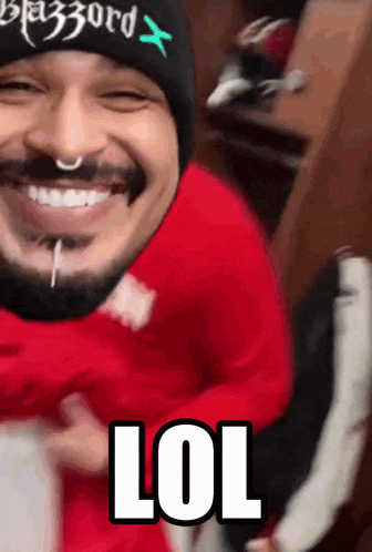 a man with a beard wearing a black beanie and a red shirt says lol