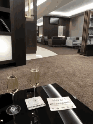 two glasses of champagne sit on a table next to a coaster that says merci milesopedia