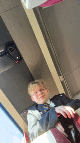 a boy in a suit and tie is sitting in a bus