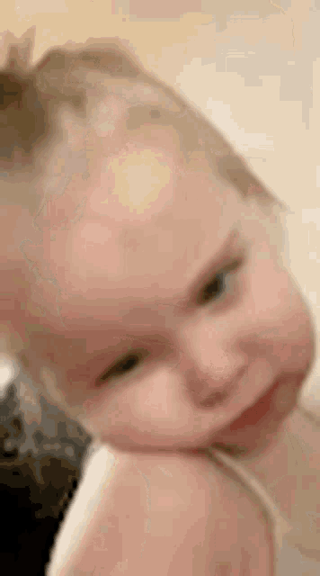 a close up of a baby making a funny face with her hand on her chin .