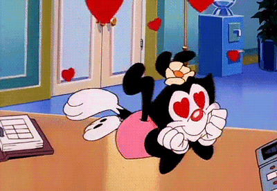 a cartoon character with heart shaped eyes is laying on a desk