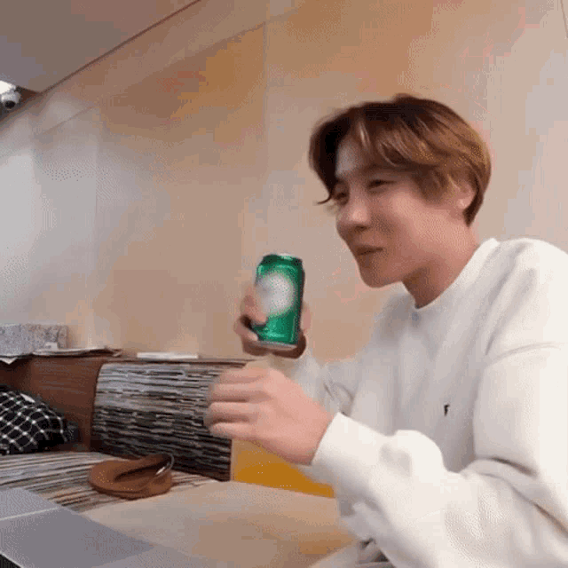 a man sitting at a table holding a can of soda