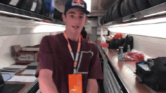 a young man wearing a red bull hat stands in a room