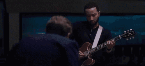 a man is playing an electric guitar in front of a man .