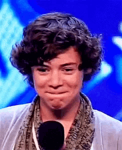 a man with curly hair is crying while standing in front of a microphone