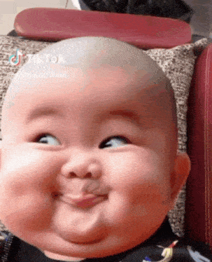 a baby is making a funny face while sitting on a pillow .
