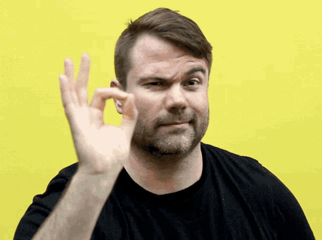 a man in a black shirt makes an ok sign
