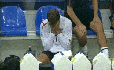 a man wearing a number 7 jersey sits on a bench with his head in his hands