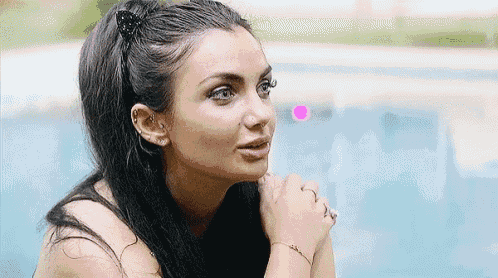 a close up of a woman 's face with her hands folded in front of a swimming pool .