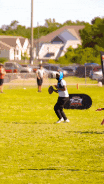 a man in a blue helmet is holding a football in a field with a sign that says 7 on 7