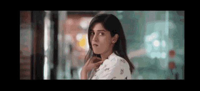 a woman in a white shirt is standing in front of a glass door .