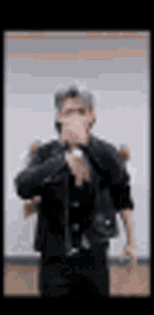 a man in a suit and tie is standing in front of a microphone in a blurry photo .