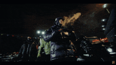 a man in a blue jacket is smoking a cigarette and giving a thumbs up sign