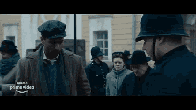 a man in a hat is talking to a police officer in front of a crowd .