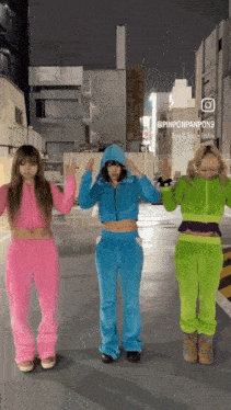three girls wearing pink blue and green outfits are standing next to each other in a parking lot