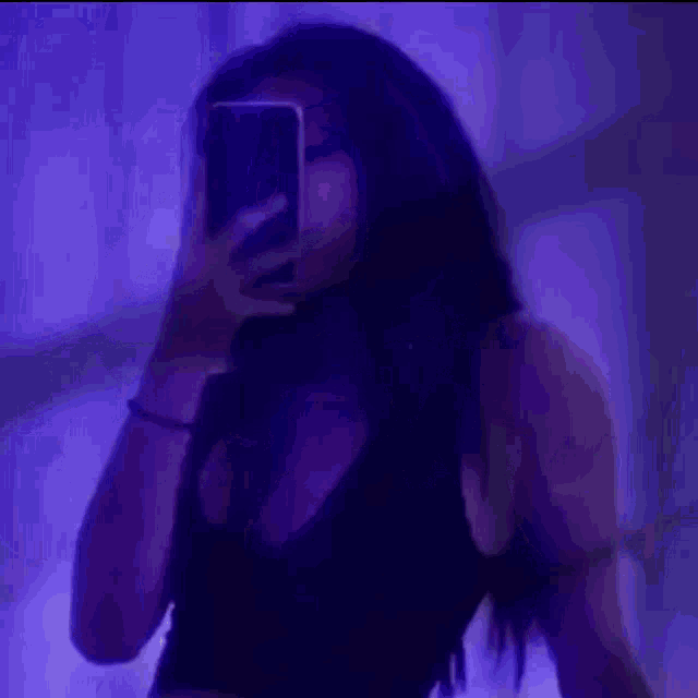 a woman is taking a picture of herself with her cell phone in a dark room .
