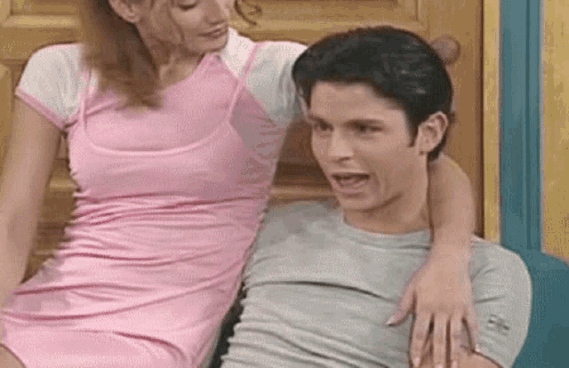 a woman in a pink dress is sitting next to a man in a gray shirt .