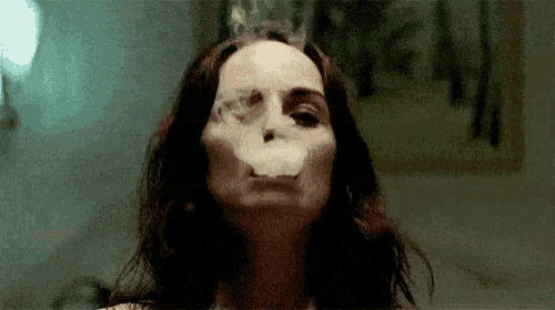 a woman is blowing smoke out of her mouth .