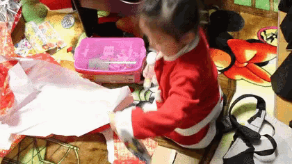 a little girl wearing a santa suit is cutting a piece of paper