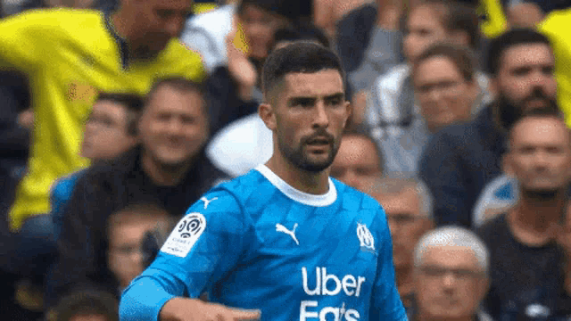 a soccer player wearing a blue uber shirt is pointing at the crowd .