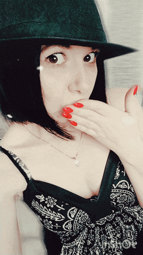 a woman with red nails wearing a black hat and a black bra