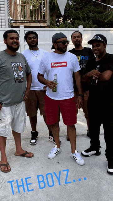 a group of men are posing for a picture and one of them is wearing a supreme t-shirt