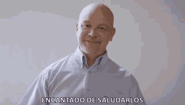 a bald man wearing a blue shirt says " encantado de saludarlos "