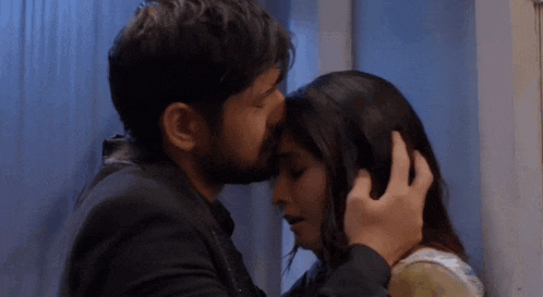 a man is kissing a woman on the forehead in a room