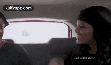 a man and a woman are sitting in the back of a car .