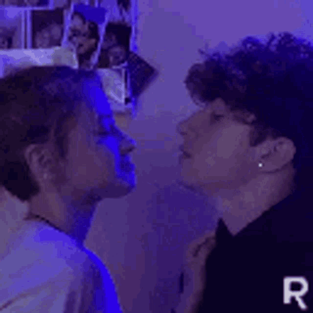 a man and a woman are kissing in front of a purple wall .