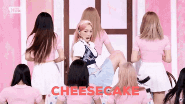 a group of girls in pink shirts and skirts are dancing with the word cheesecake in red