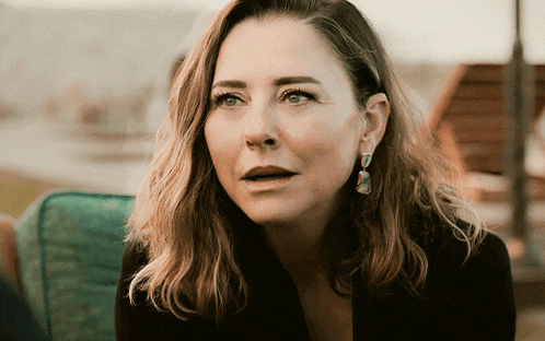 a close up of a woman wearing earrings and a black jacket