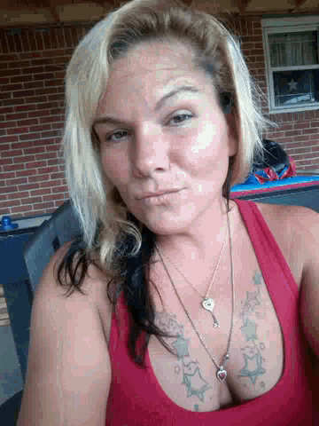 a woman in a red tank top has a necklace with a heart on it