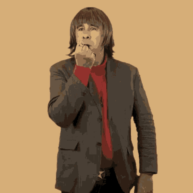 a man in a suit and red turtleneck is giving the middle finger