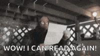 a man is holding a piece of paper with the words `` wow ! i can read again ! '' written on it .