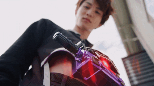 a man in a black shirt is holding a purple and red object