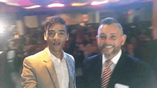 a man in a suit and tie is standing next to another man