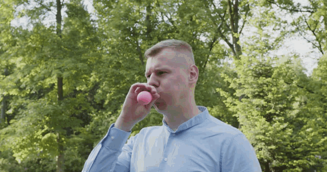 a man in a blue shirt blows a pink ball