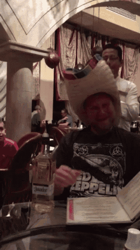 a man wearing a cowboy hat and a zeppelin shirt is sitting at a table