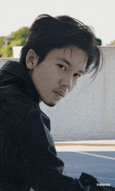 a young man in a black jacket is looking at the camera with runway written on the bottom right