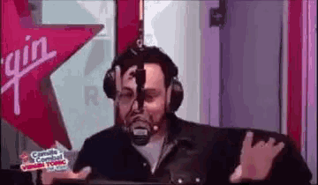 a man wearing headphones is standing in front of a microphone in a radio studio .