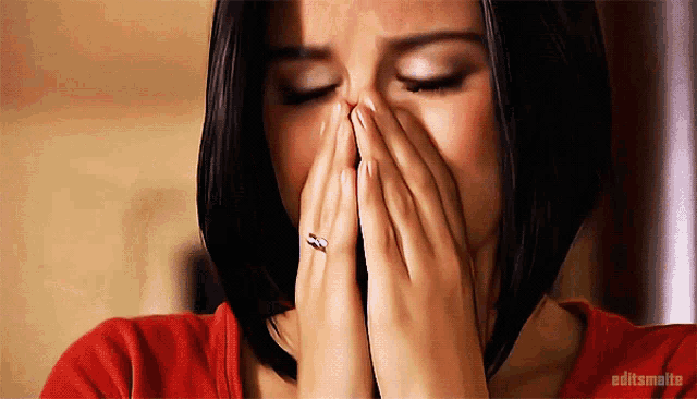 a woman with a ring on her finger is covering her face