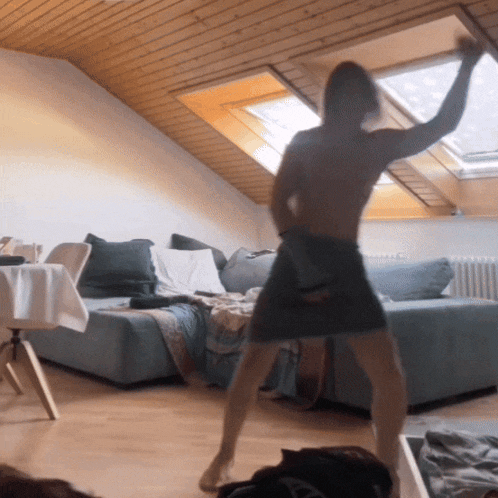 a woman dancing in a living room with a skylight